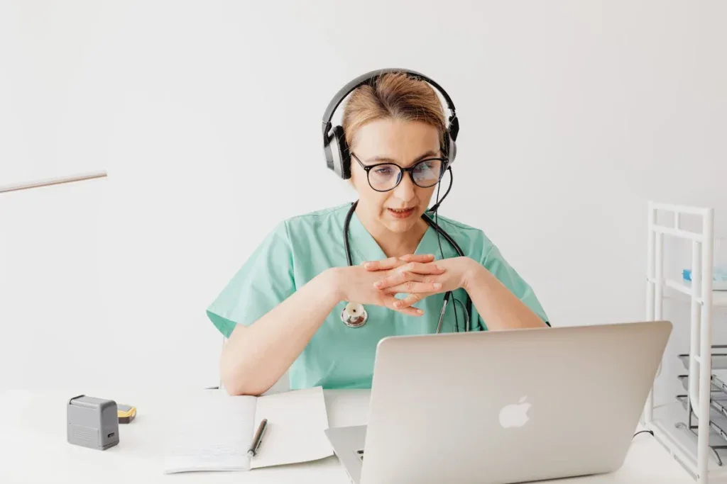 a nurse sitting at a table using a laptop computer