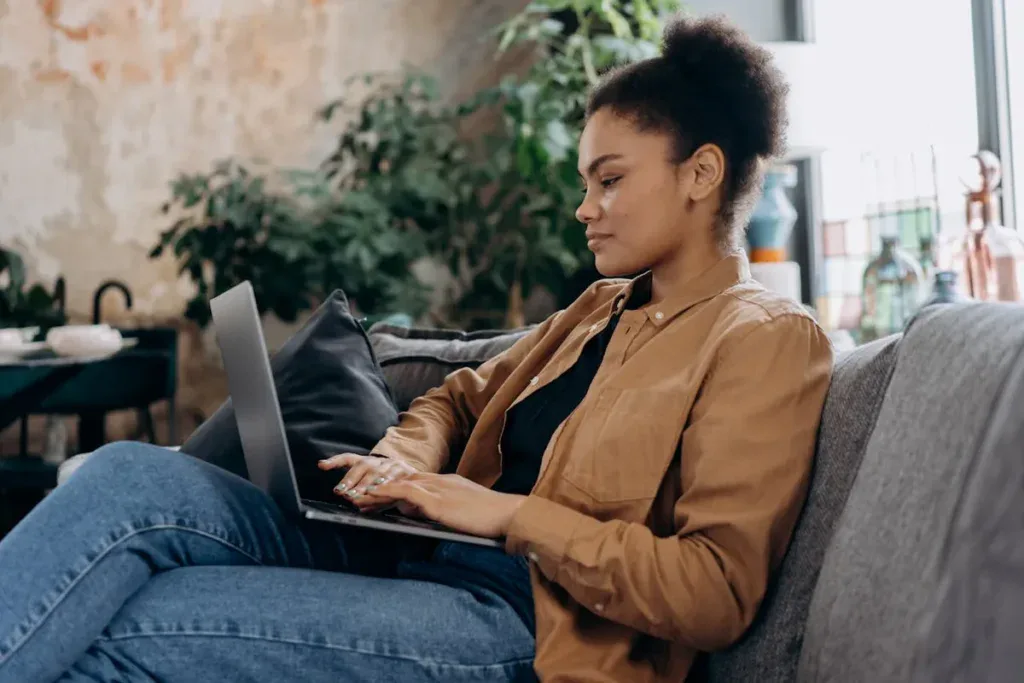 Person sitting on a couch while working on their laptop
