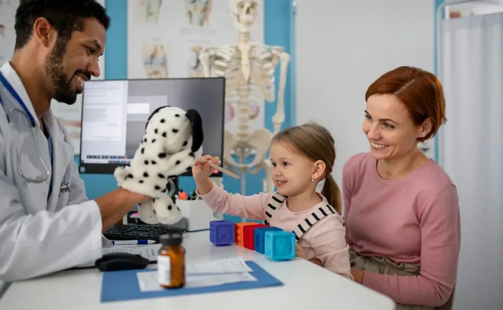 Doctor talking to mom and child while showing a toy